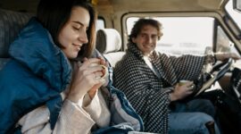 Young couple enjoying a road trip while driving a vehicle, representing beginner driver experience and driving practice.